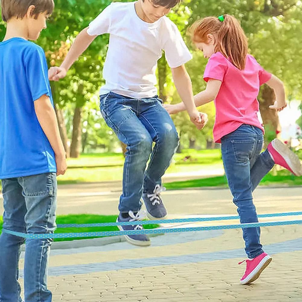 Bambini che allungano il giocattolo all'aperto classico del gioco dei bambini della corda di salto dell'elastico elastico