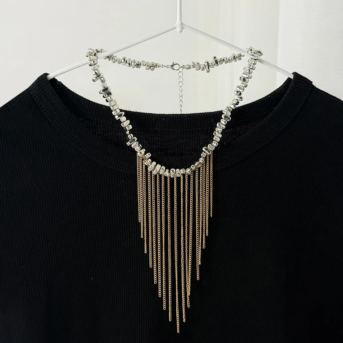Collana da donna con design transfrontaliero, catena sottile in metallo argentato irregolare e frantumato, con nappe e perline, a clavicola.