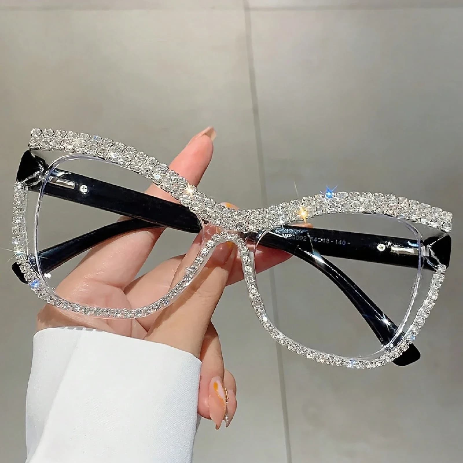 Un paio di occhiali piatti da donna alla moda con montatura cat-eye e decorazioni in strass, adatti per le uscite quotidiane e le feste.