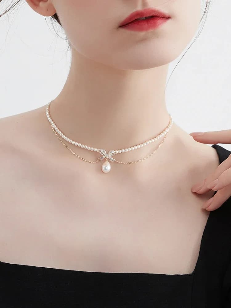 Collana con doppio fiocco e perle finte, accessorio da collo per donna dallo stile raffinato.