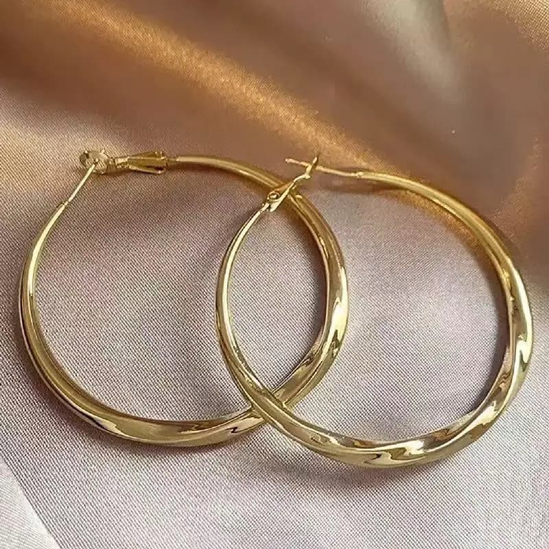 Un paio di orecchini dorati, gioielli alla moda, indossati dalle donne nella vita quotidiana. Grandi orecchini che rendono la festa elegante e raffinata
