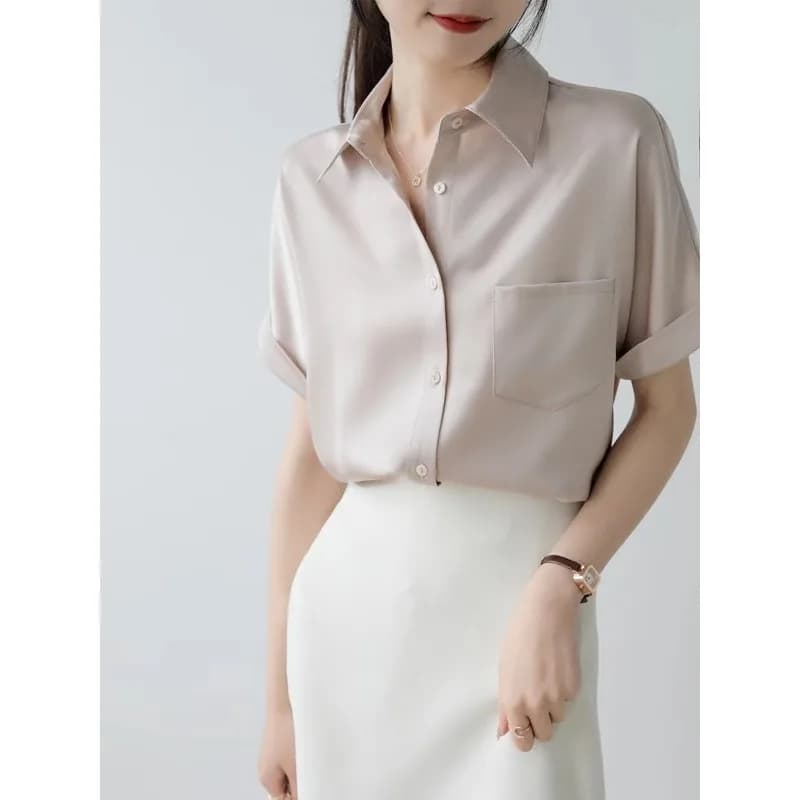 Camicia da donna a maniche corte con bottoni e taschino sul petto, disponibile in diversi colori.