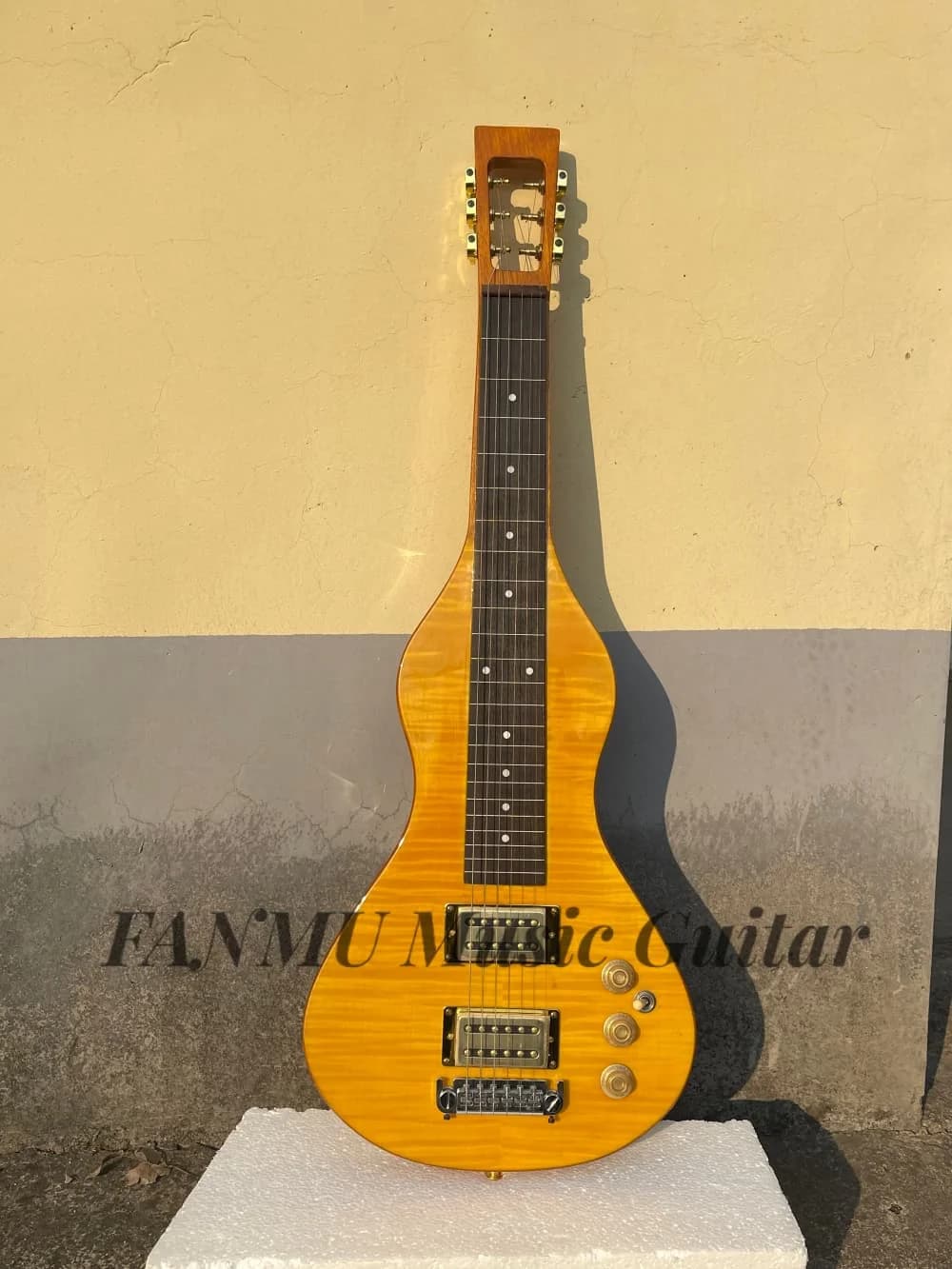 Chitarra hawaiana a 6 corde, con top in acero fiammato, corpo in legno massello, ponte fisso, pickup dorati, paletta scavata.