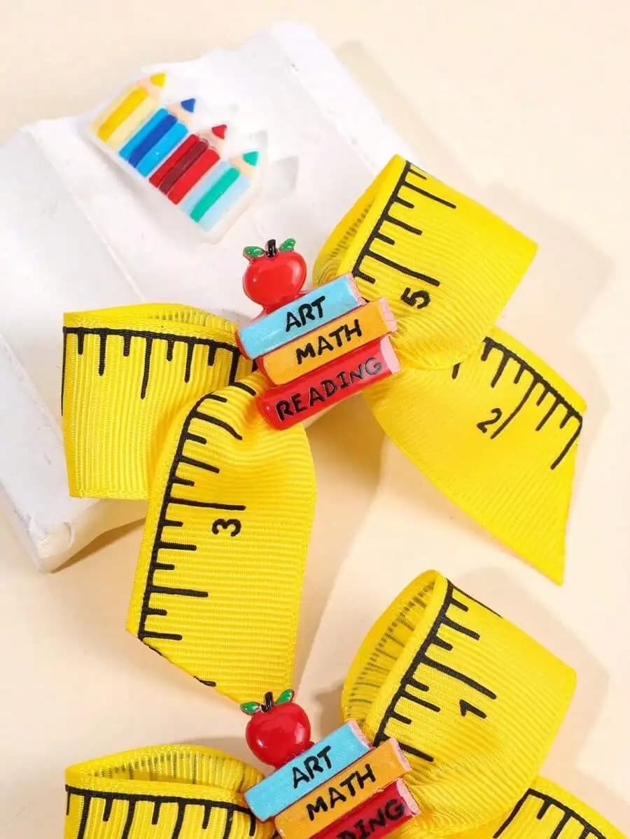 2 girl hair clips for return to school, with yellow ribbon shaped like a ruler and pendants in book shape and apple