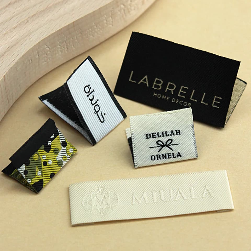 Etichetta tessuta piegata al centro personalizzata LOGO etichette in tessuto a grana Twill goffrato cucire su abbigliamento ricamo tessile etichetta collo/orlo