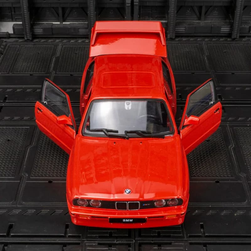 Modellino auto in lega Bburago 1:24 BMW M3 E30 con porte, cofano e bagagliaio apribili, adatto per collezionismo.