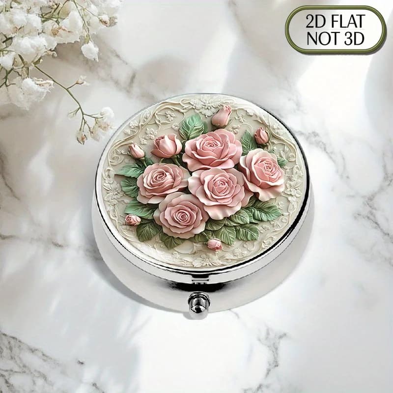 A flat, portable, round metal pill box with a pink rose and green leaf design, stylish for storing medicines and supplements, suitable for organizing vitamins, small accessories, or as a travel gift, a perfect choice for loved ones