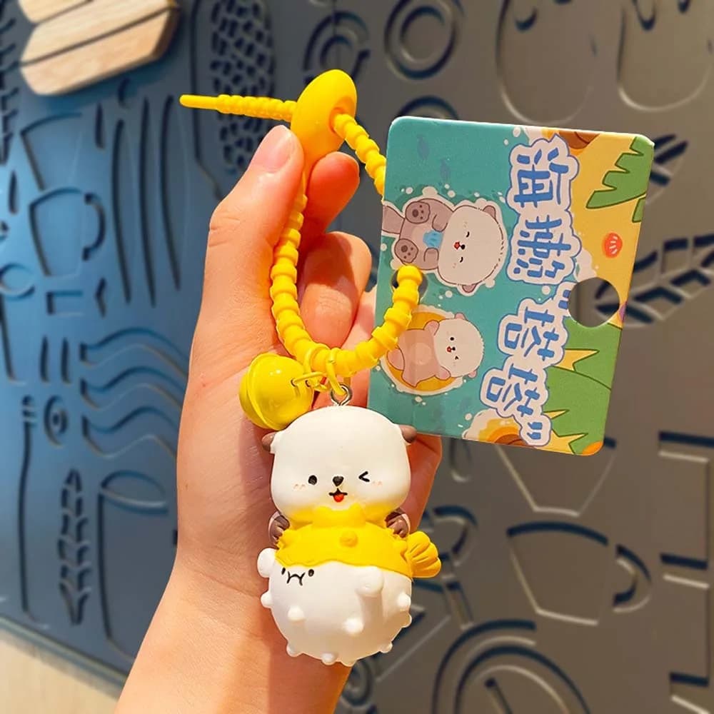 Portachiavi in PVC a forma di lontre dei cartoni animati, accessorio per chiavi, ciondolo per borsa a forma di lontre che tiene una pesce, con anello e campanello