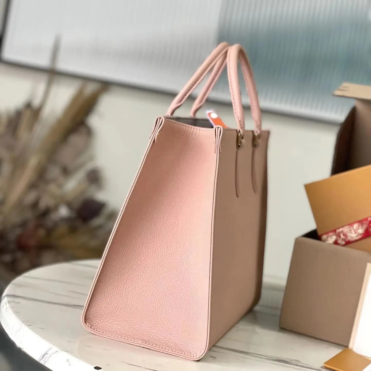 Borsa a mano strutturata in pelle granulare rosa cipria con manico superiore.