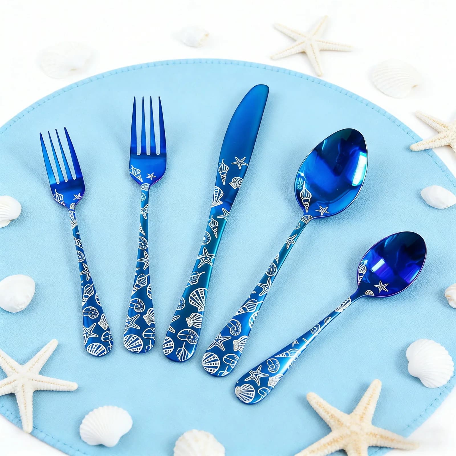 Set of blue stainless steel cutlery, knives, forks and spoons with laser engraved shell design, mirror finish.
