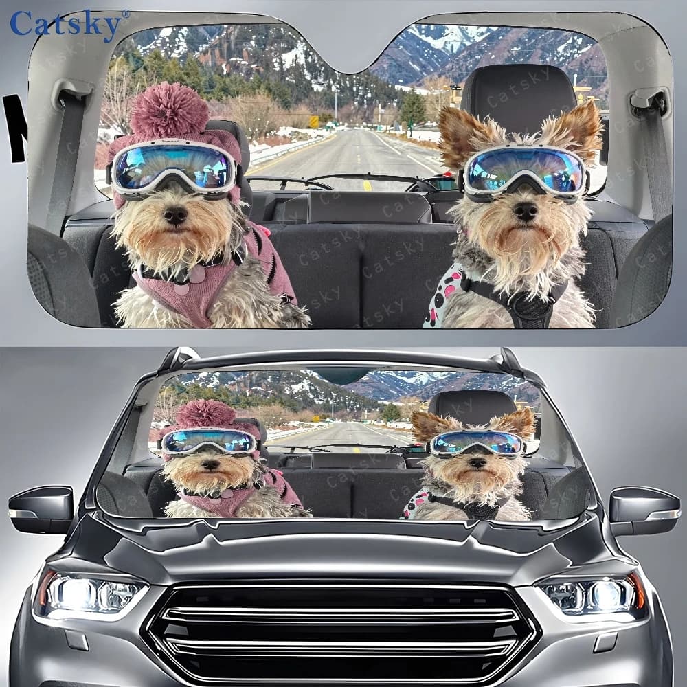 Two Little Dogs With Ski Goggles Are Perched In The Rear Seat Of A Vehicle, Surrounded By Car Sunshades And A Front Window Cover