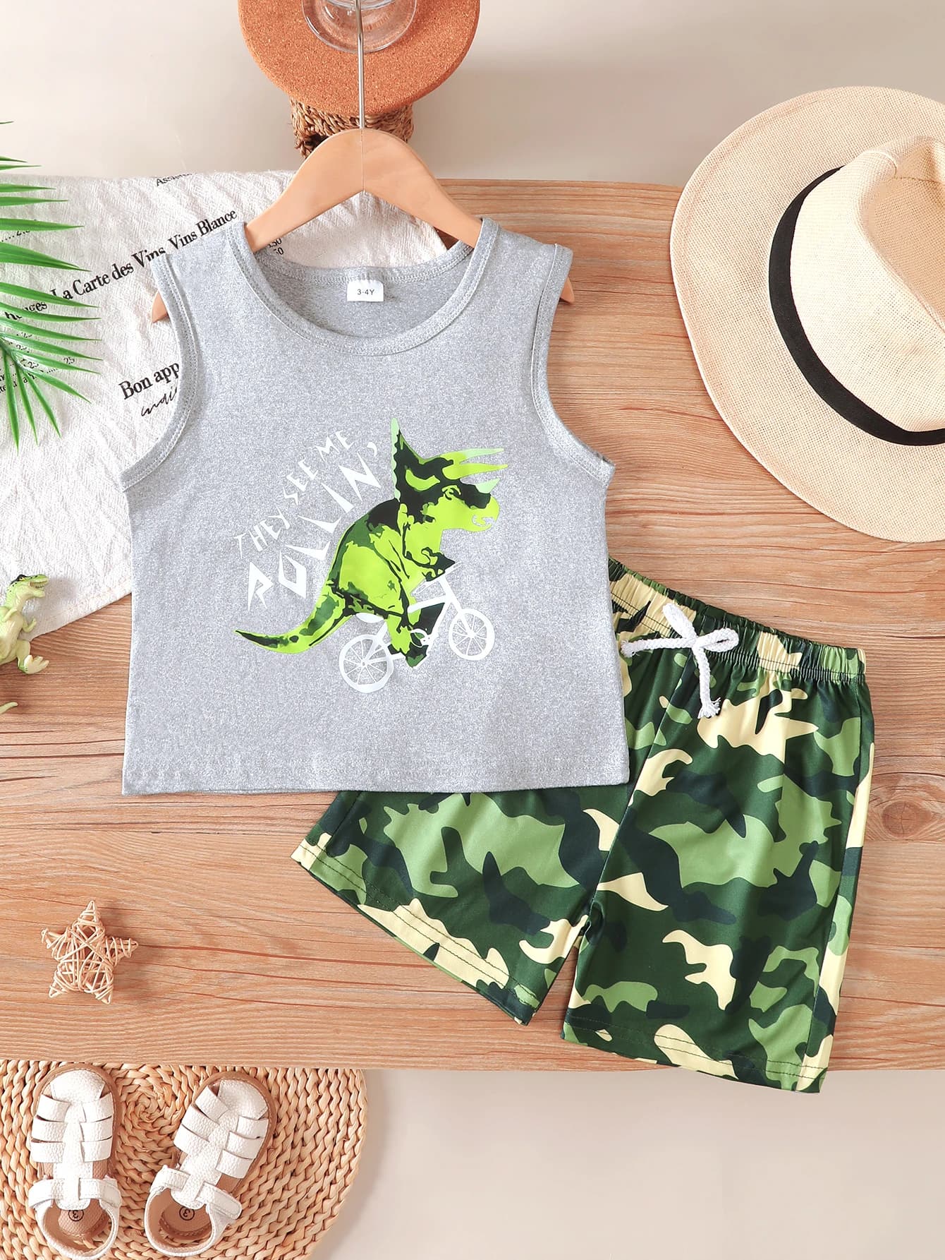 Boys' Summer Sleeveless Vest and Shorts Two-Piece Set, Featuring a Fun Dinosaur Cycling Print Top Paired with Camouflage Drawstring Shorts, Made from Comfortable and Breathable Fabric, with a Casual Loose Fit, Suitable for Little Boys' Daily Outings, Outdoor Activities, and Vacation Wear.