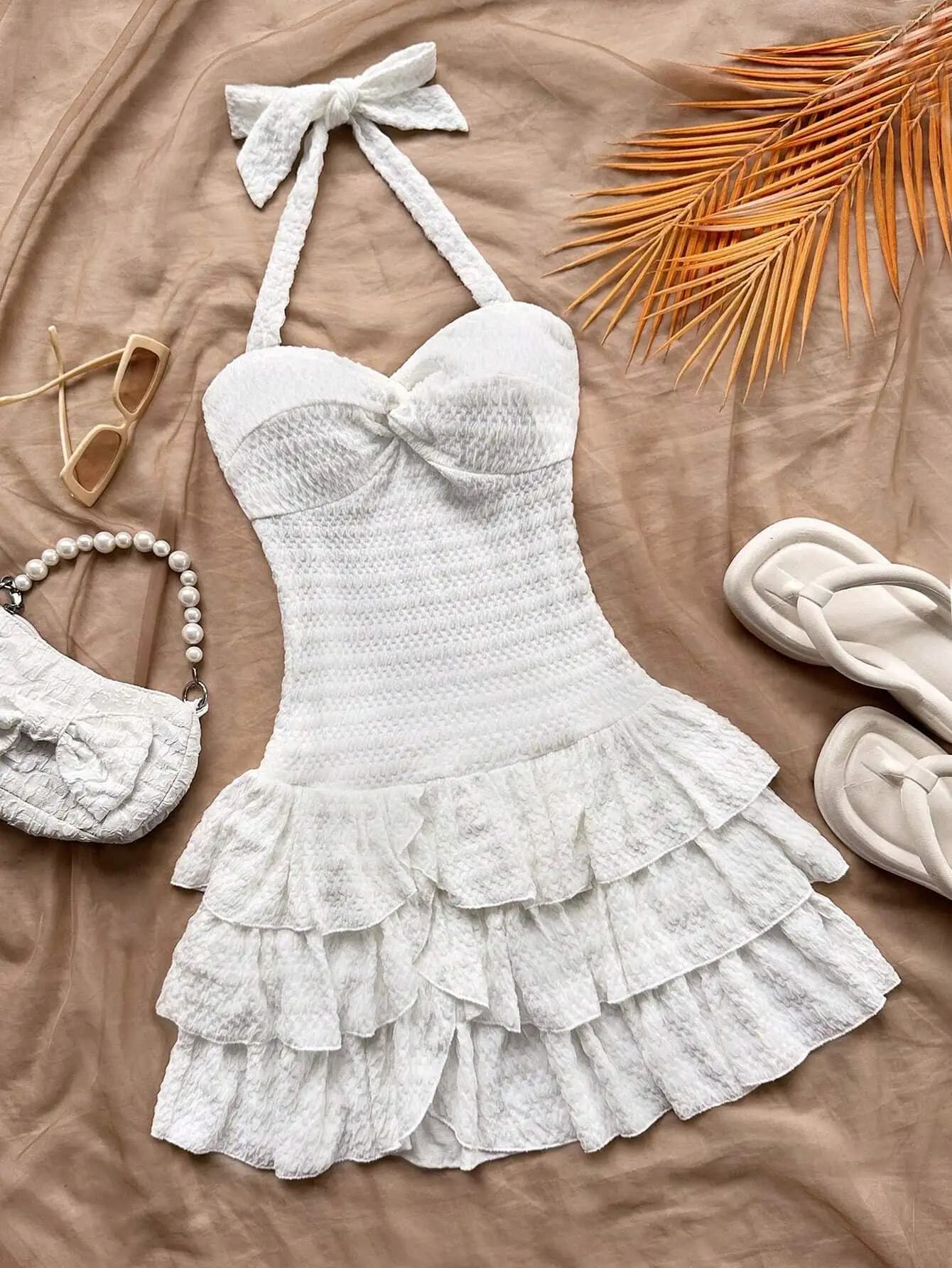 Mini abito bianco con scollo all'americana, busto arricciato, balze a strati e fiocco