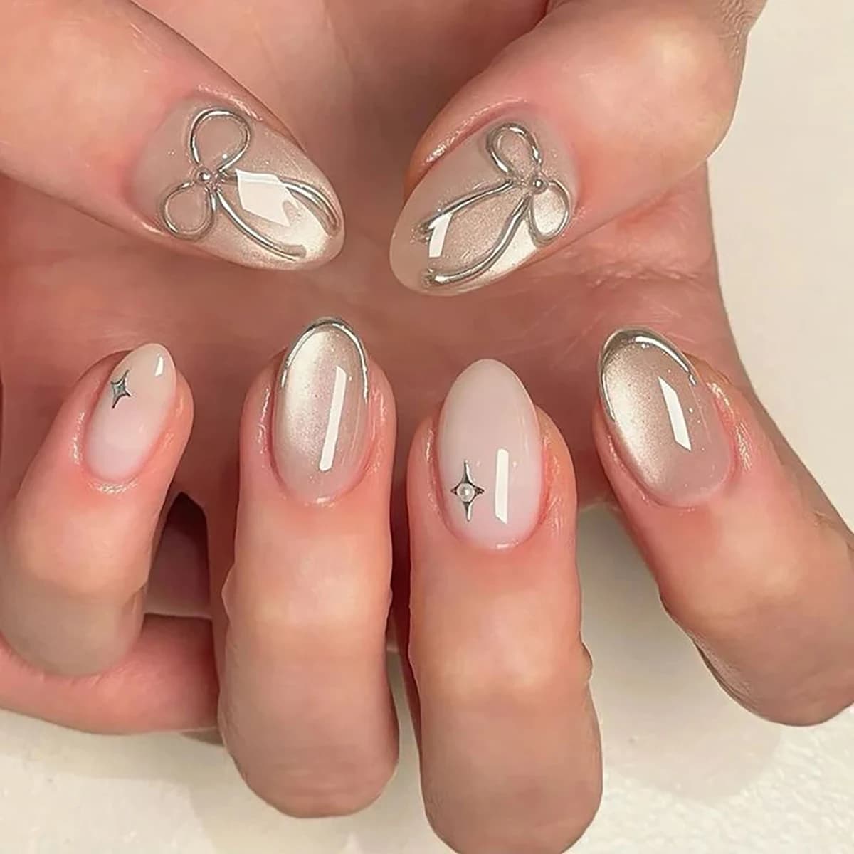 24pcs handmade short round press-on nails. Shimmer cream base with silver French tips, 3D bows & star studs. Reusable, ideal for
