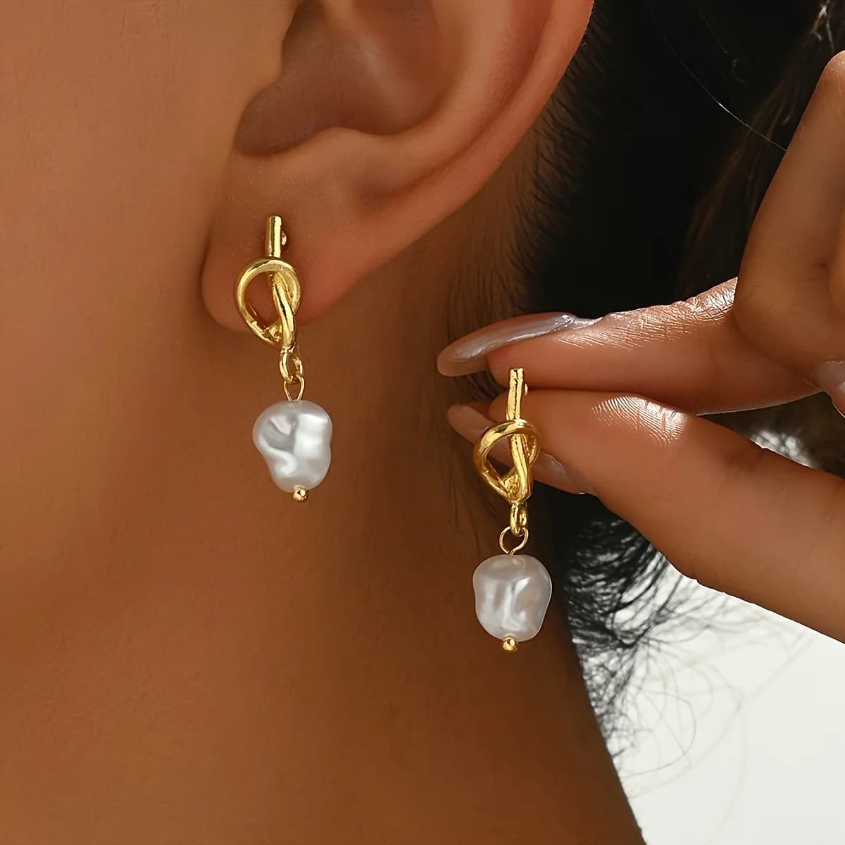Delicati orecchini pendenti con perle barocche e nodo in oro.