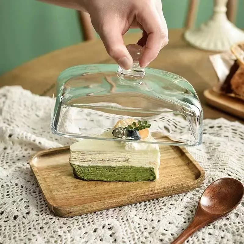 Piatto da burro in vetro con coperchio in vetro cristallo contiene cubetti di formaggio crema e piatti di piatti e piccoli frutti