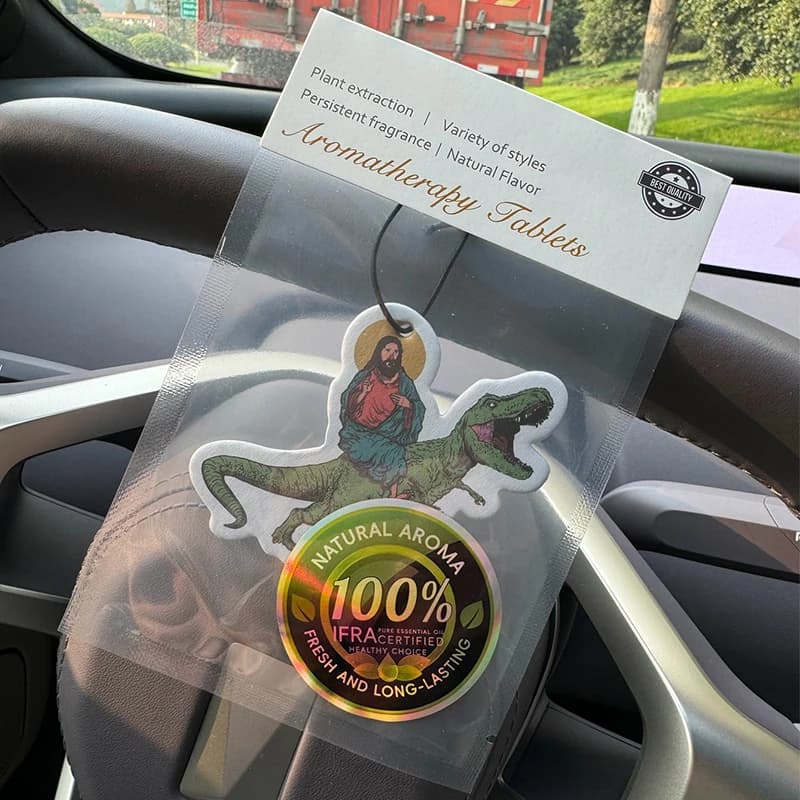 Deodorante per Auto 'Praise Jesus Riding a Dinosaur' (Profumo da Hotel) | Ciondolo per specchietto retrovisore e clip per bocchetta dell'aria a doppio uso | Pastiglie per Aromaterapia in Materiale Naturale | Fragranza a Lunga Durata per 90 Giorni | Non Alcolico | Non temo il sole | Appositamente Progettato per Deodorare Auto, Armadi e Bagni. | Motivi di Cartoni Animati | Unisex | Fragranza di Lusso | Cinque