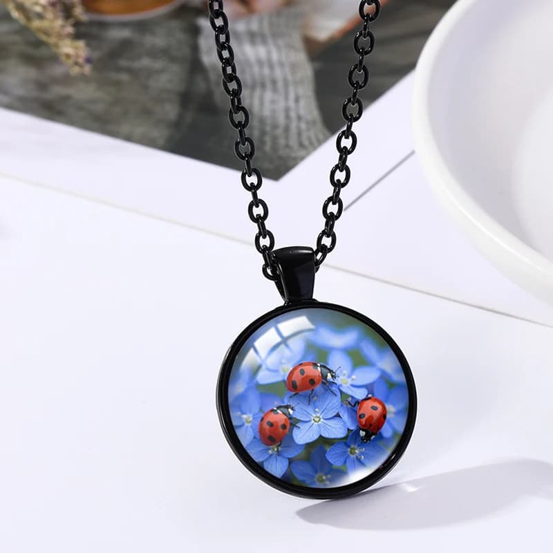Necklace of handcrafted jewelry with round black pendant with glass dome with image of red ladybugs and do not forget