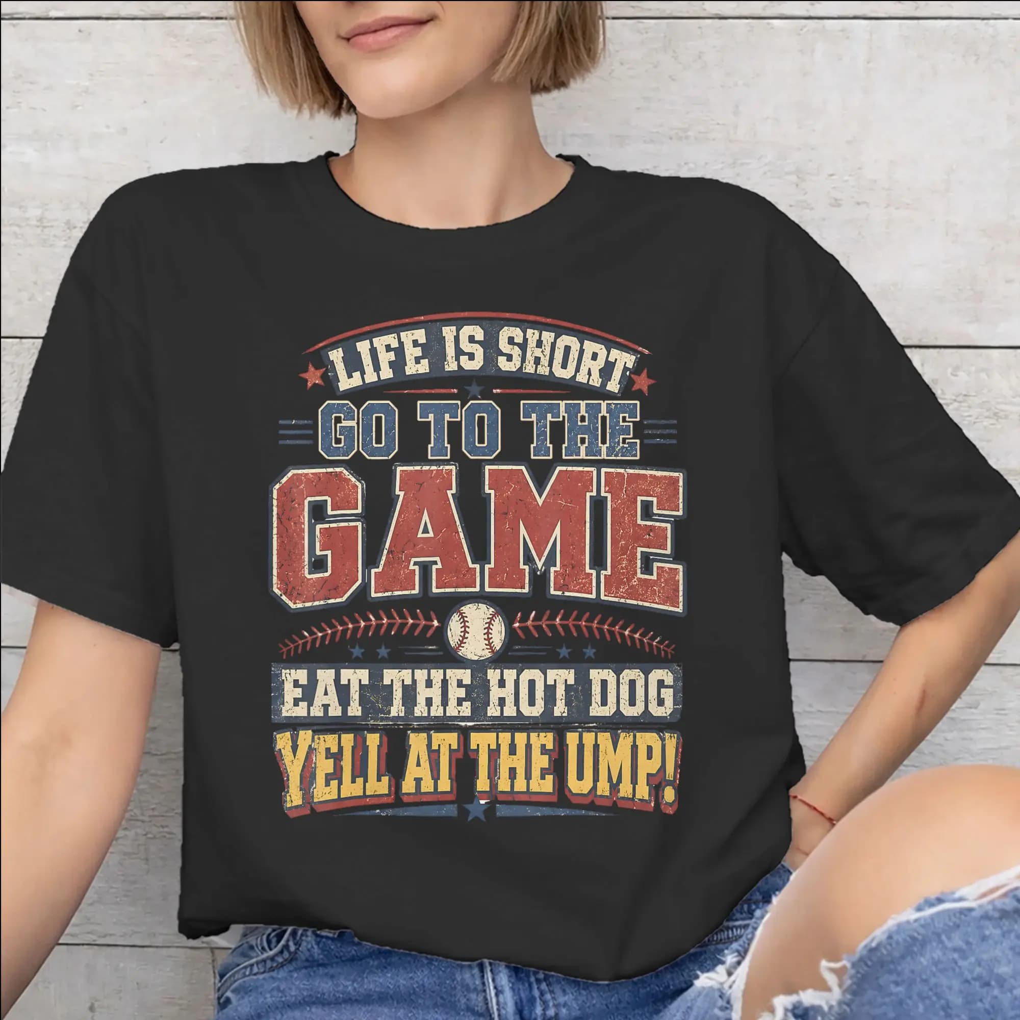 Maglietta stampata con scritta 'Life is Short Go to The Game Eat The Hot Dog Yell At The Ump' per unisex, in cotone, a maniche corte.