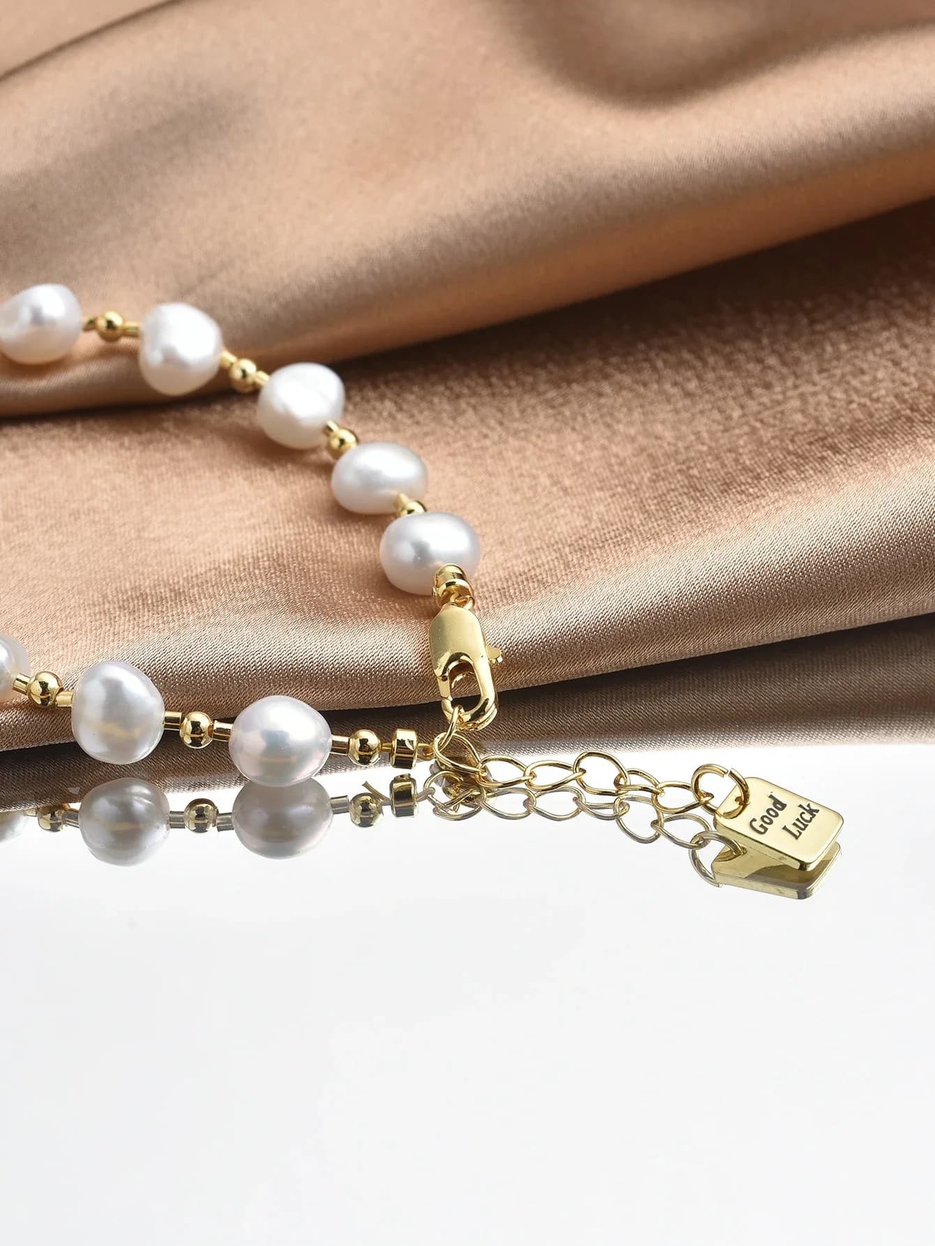 Bracciale con perle e chiusura placcata oro con ciondolo portafortuna per donna
