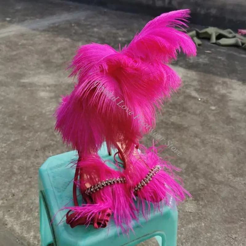 Sandali con tacco alto a punta aperta, con piume lunghe fucsia, strass scintillanti, cinturino alla caviglia e cut-out, stile passerella