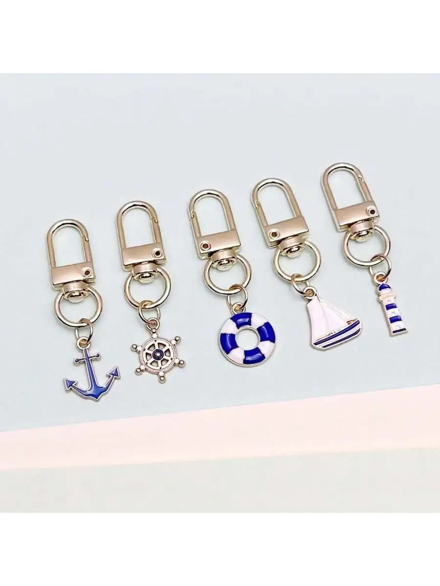 Set di 5 portachiavi nautici con ciondoli a forma di ancora, salvagente, barca a vela e faro, per decorare borse, zaini e auto.
