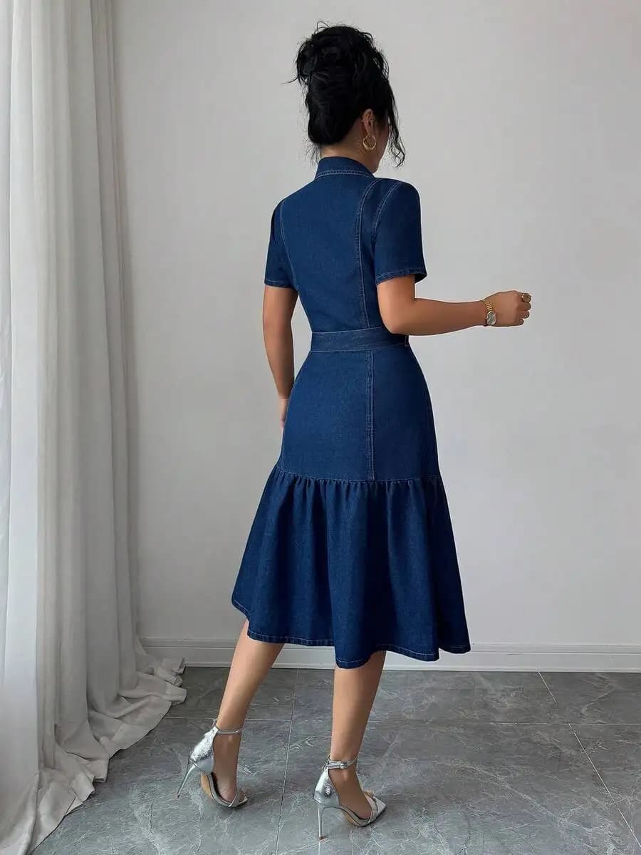 Abito midi in denim blu lavato con colletto a camicia, maniche corte, chiusura frontale con bottoni, gonna a balze e cintura annodabile.
