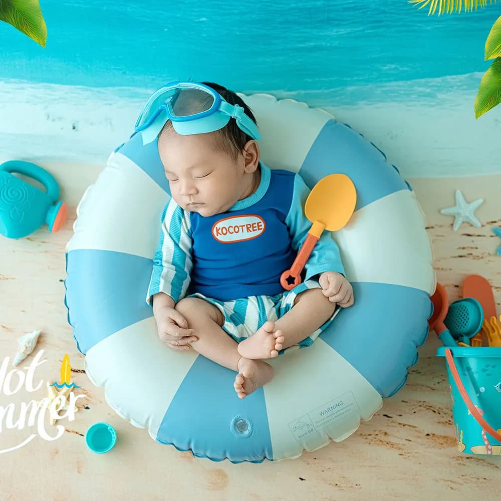 Set of beach style summer themed dresses for newborn from 0 to 1 month with swimming ring and baby glasses and photographer