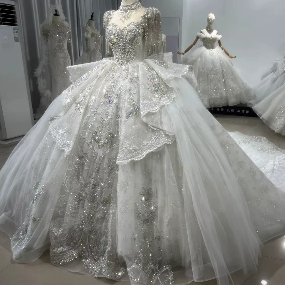 Abito da sposa con perline e cristalli, schiena allacciata, maniche corte con nappe, stile ball gown.