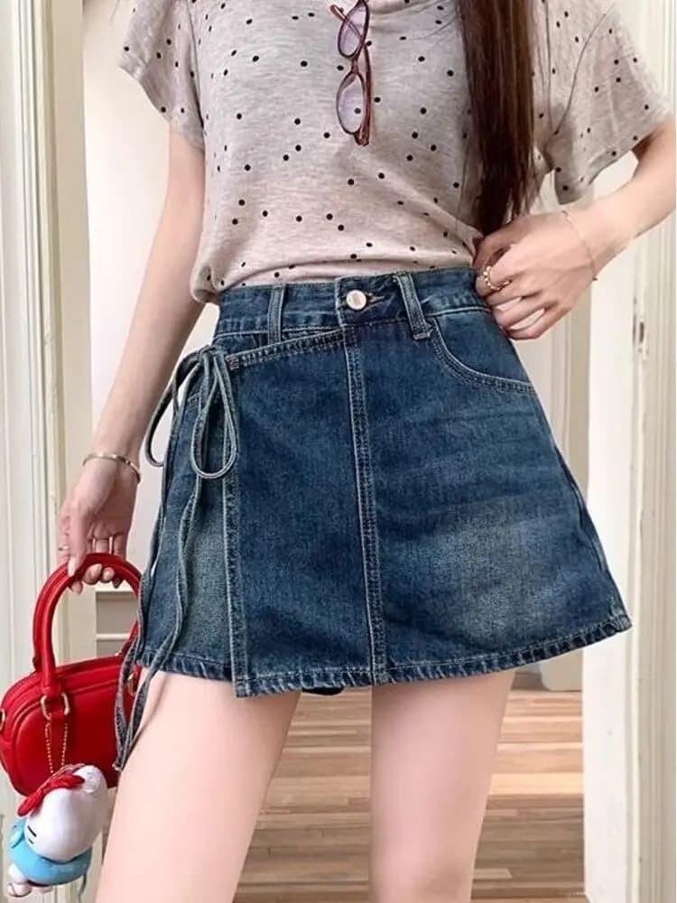 Gonna-pantalone in denim da donna a vita alta, lavaggio azzurro chiaro, effetto distressed vintage, con orlo sfrangiato e nodo asimmetrico sul davanti