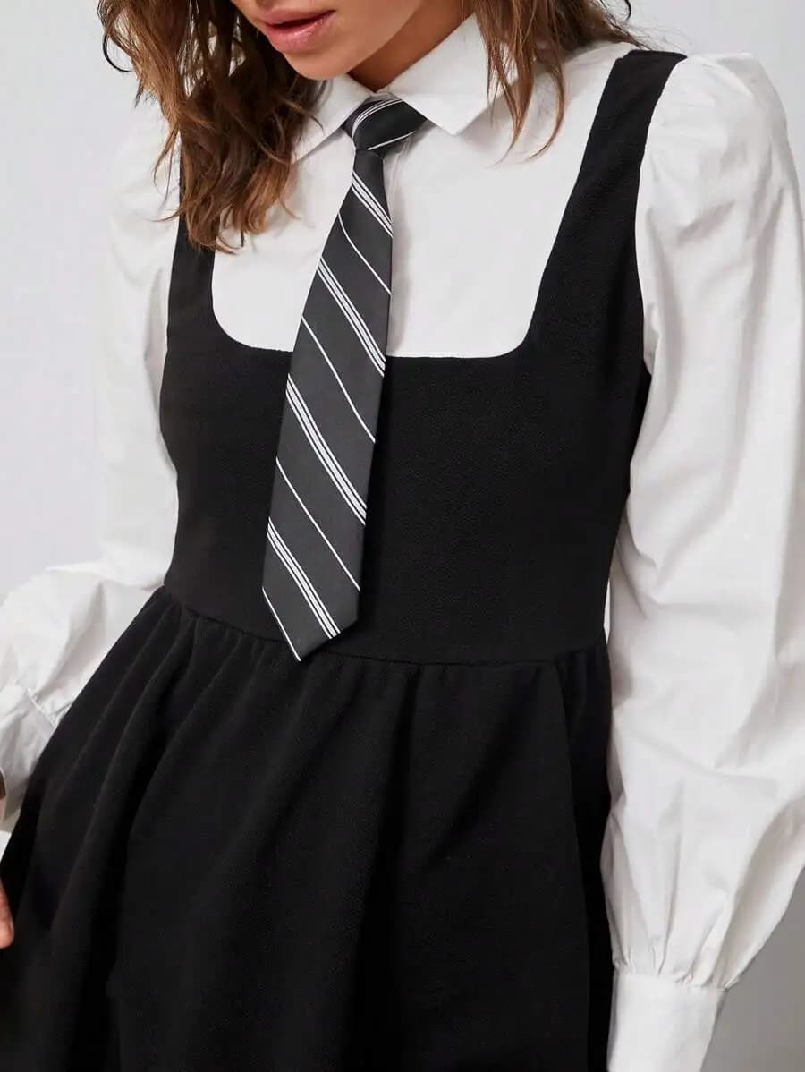 Abito nero con maniche a sbuffo, camicia bianca e cravatta a righe