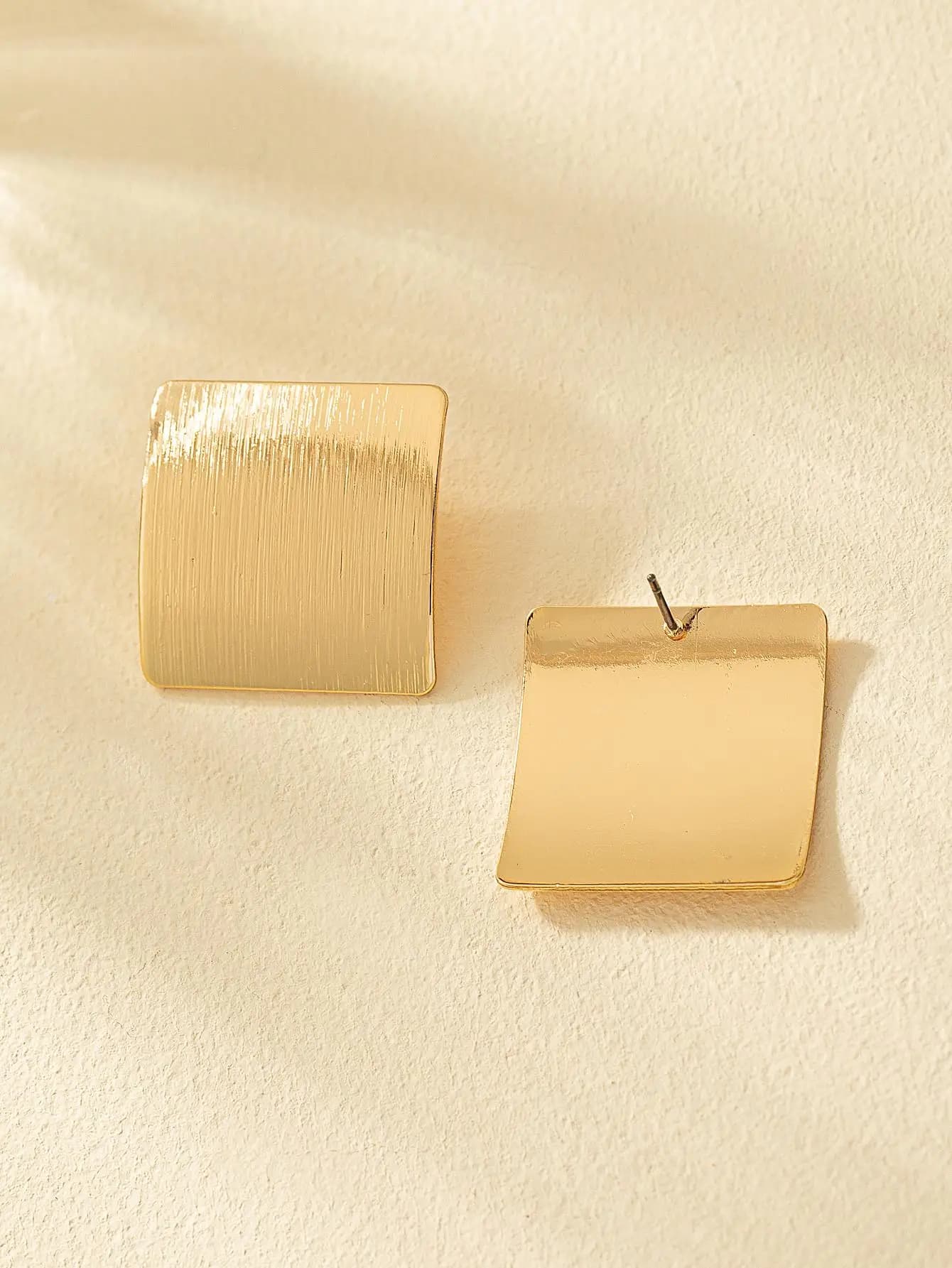 Due orecchini a perno quadrati color oro con finiture testurizzate e lisce da donna