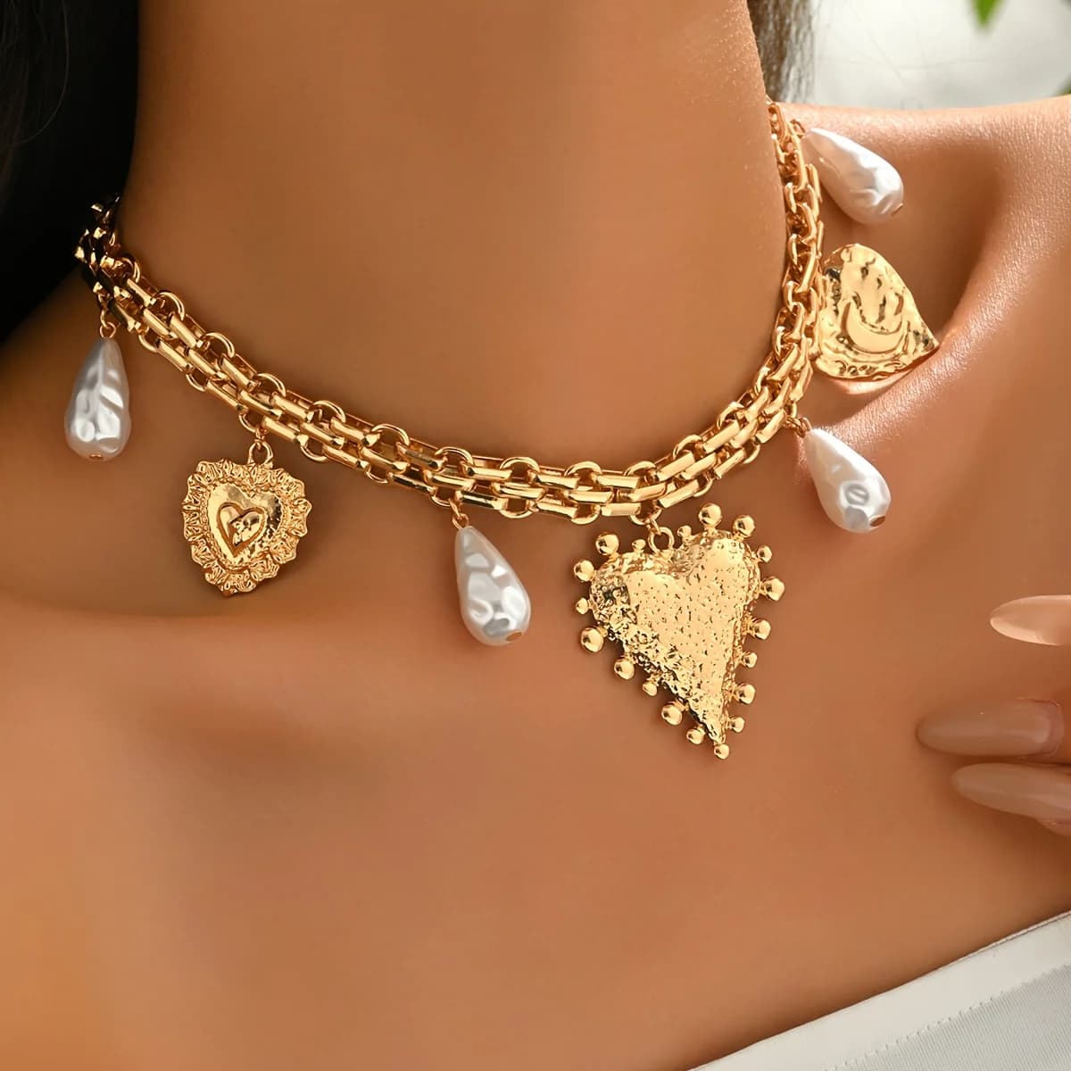 Un singolo gioiello con una collana a catena in metallo che si avvolge sulla clavicola, decorata con perle finte e un design particolare.
