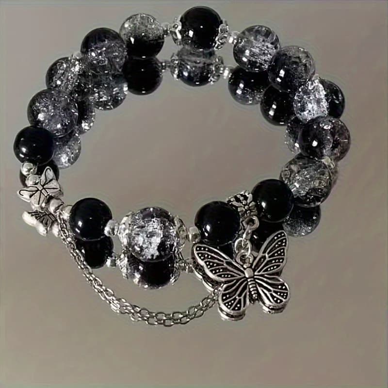 A black beaded bracelet with bohemian style, adorned with silver butterfly pendants and chain details. A distinctive gothic accessory that adds a standout touch to casual outfits. Ideal for daily wear, vacations, and a perfect gift choice for trips
