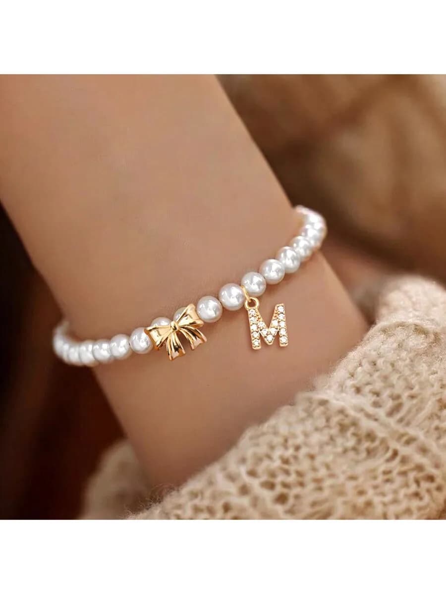 Delicato braccialetto di perle con fiocco placcato oro e ciondolo iniziale M scintillante per donna